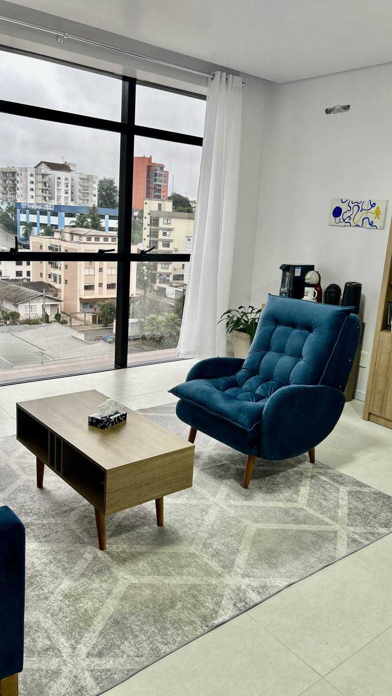 Detalhe do consultório com poltrona de leitura e estante